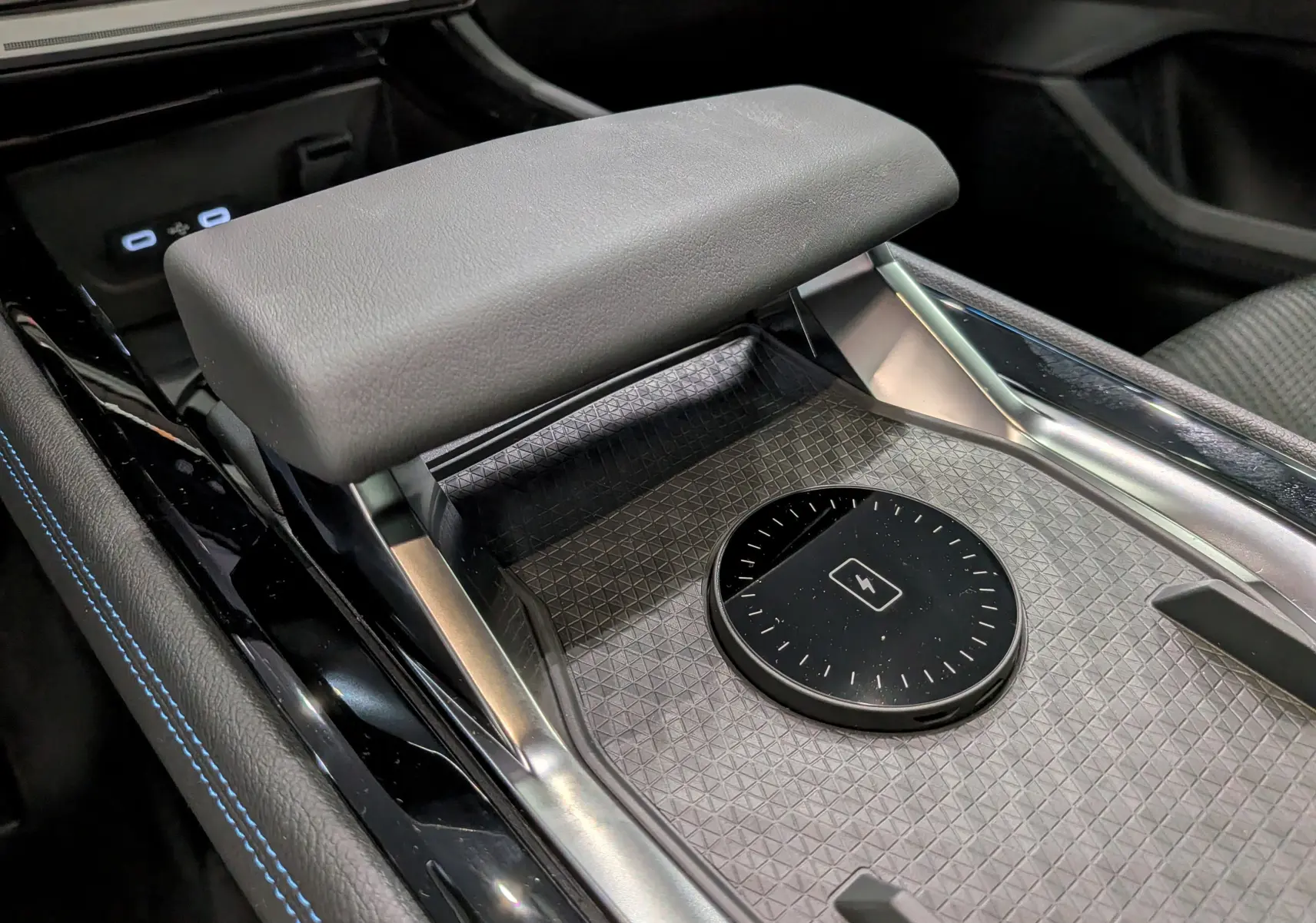 Détail intérieur du Renault Austral full hybrid, montrant le chargeur sans fil et l'accoudoir en cuir gris.