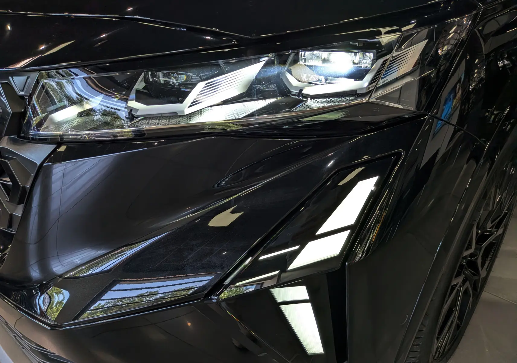 Gros plan sur le phare avant droit noir brillant du Renault Austral full hybrid Esprit Alpine 2026 avec éclairage LED distinctif.