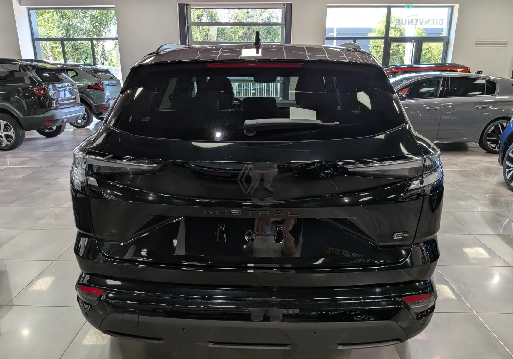 Vue arrière d’un Renault Austral noir full hybrid E-Tech 200 ch Esprit Alpine en showroom, avec feux LED fins et logo central.