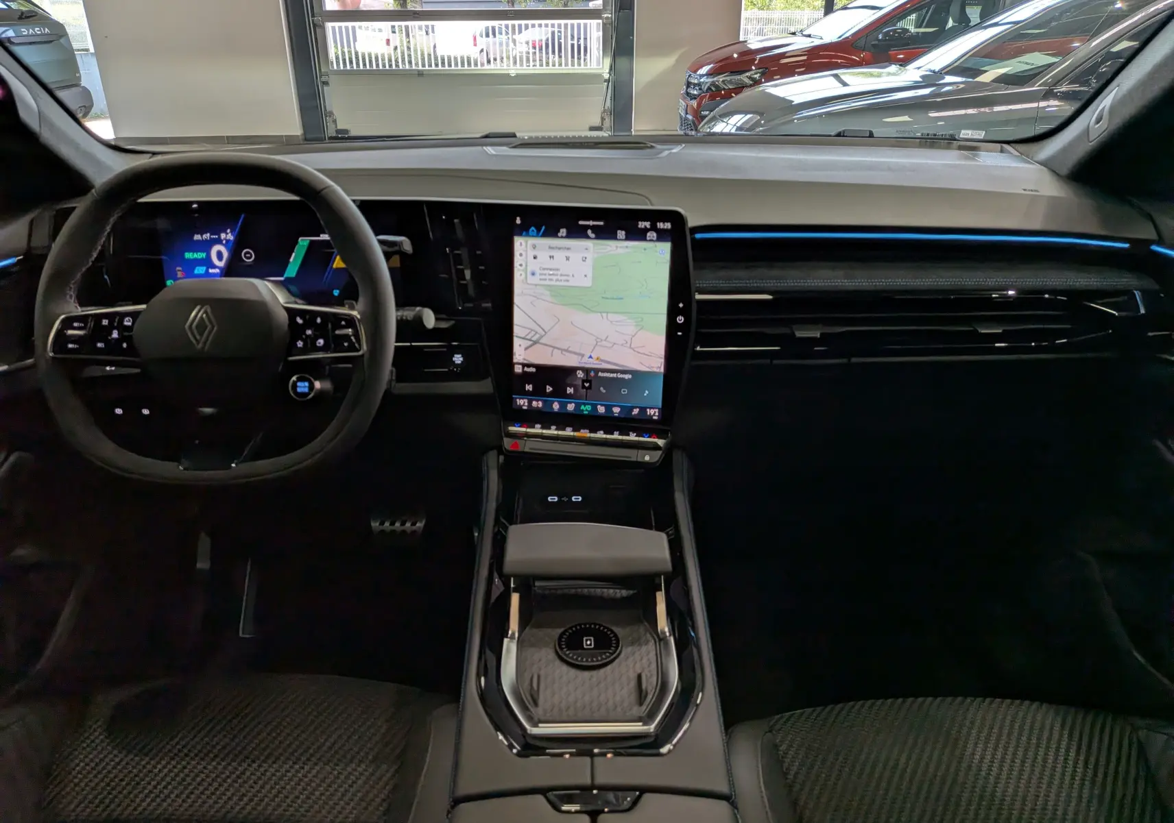 Vue intérieure frontale du tableau de bord noir du Renault Austral full hybrid avec écran tactile central vertical et volant multifonction.