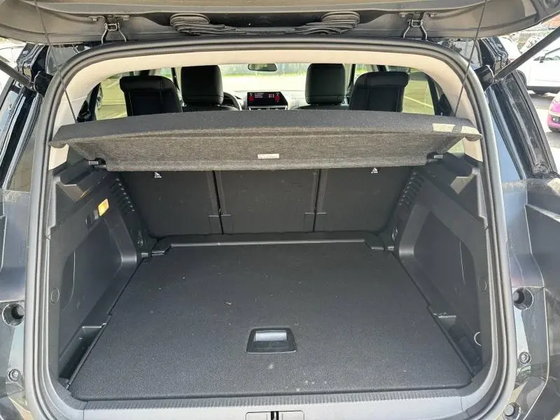 Coffre ouvert vu de l'arrière d'un Citroën C5 Aircross noir Perla Nera avec cache-bagages et intérieur spacieux.