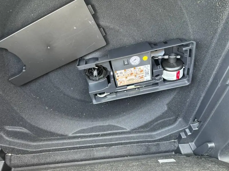 Détail du compresseur de pneu intégré dans le coffre du Citroën C5 Aircross 2025 Noir Perla Nera.
