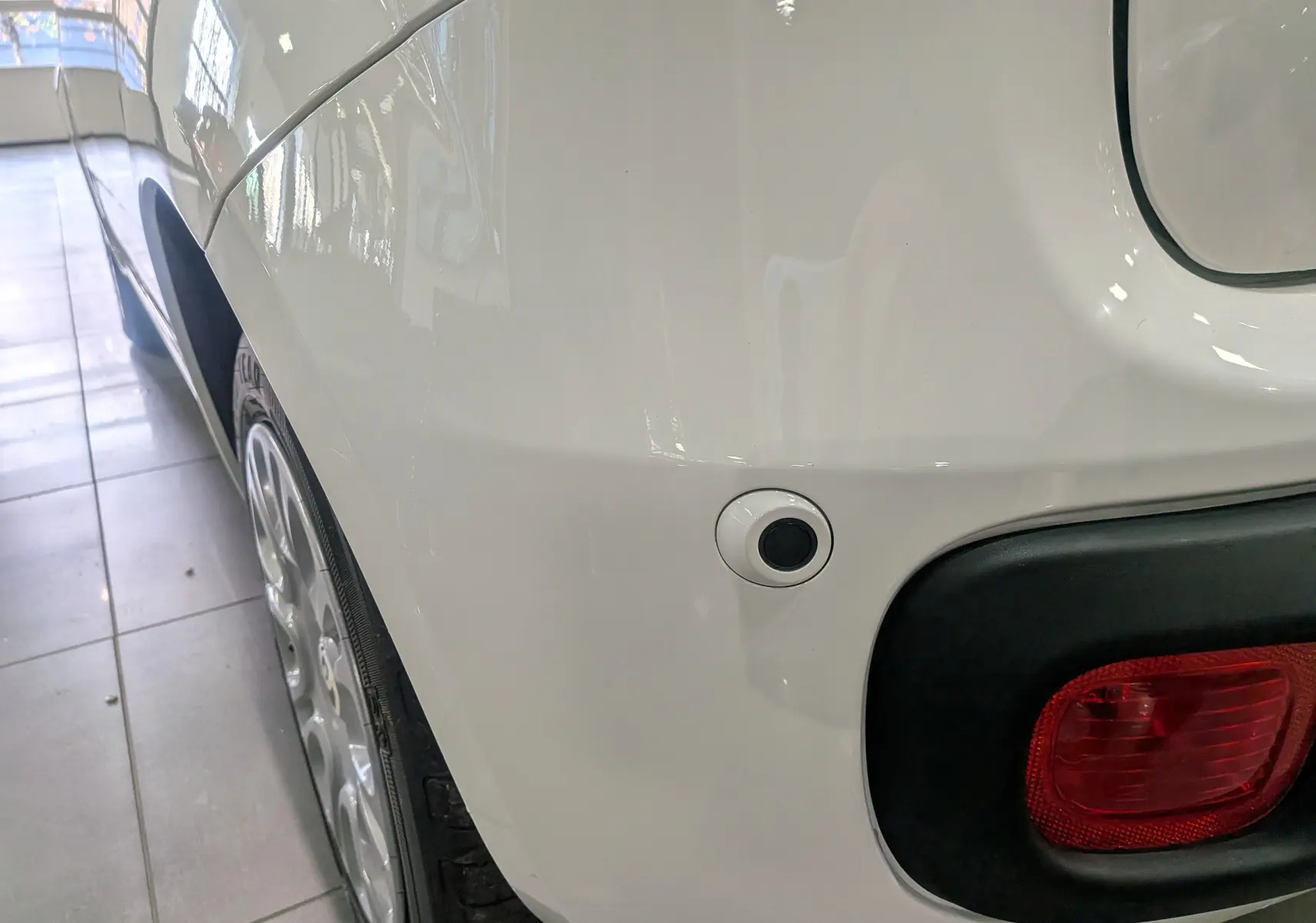 Gros plan sur l’aile arrière droite blanche Gelato de la Fiat Panda 1.0 70 CH Hybrid City avec feu arrière et capteur de stationnement.