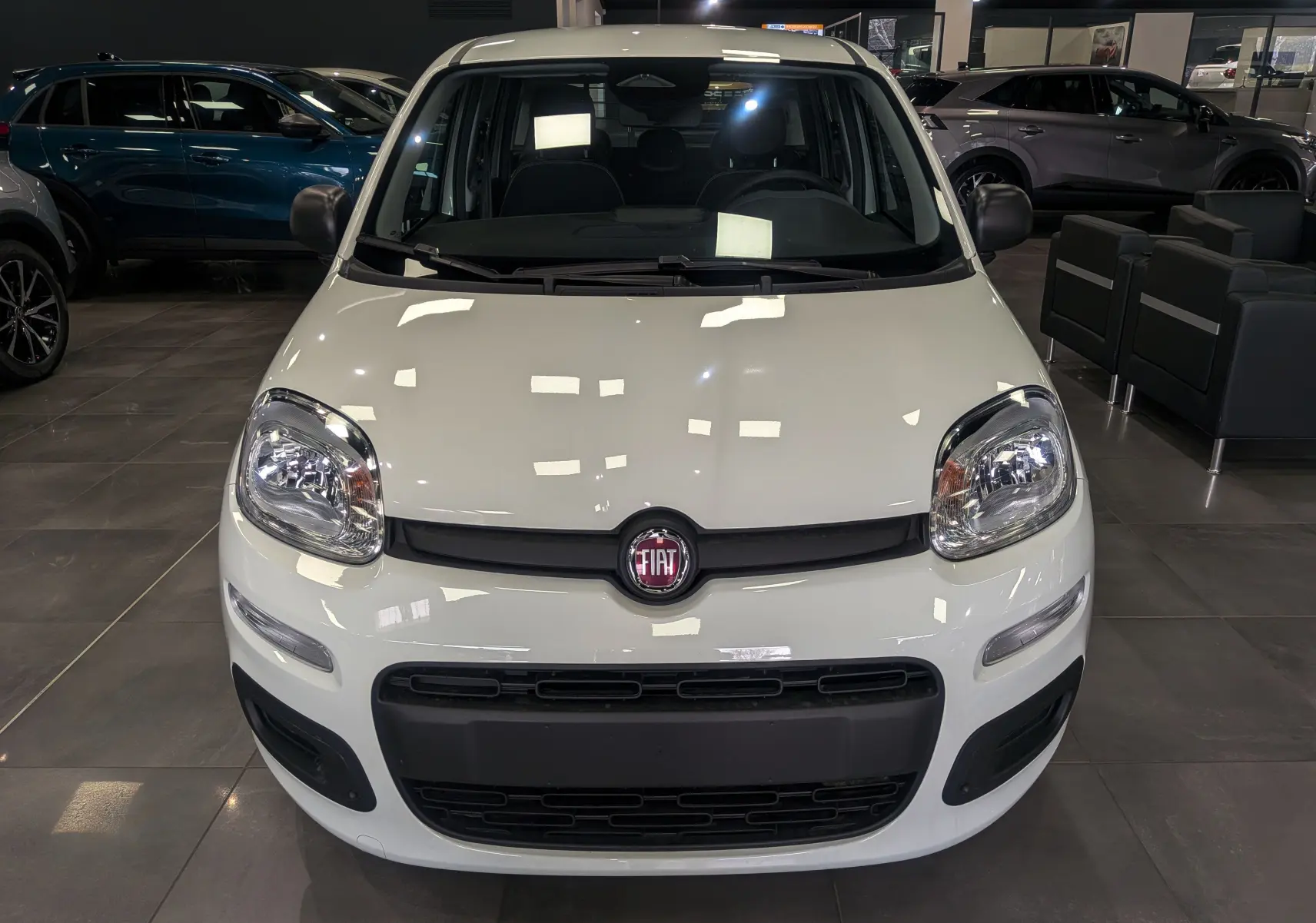 Vue de face d'une Fiat Panda 1.0 70 CH Hybrid City blanche Gelato, avec calandre noire et logo Fiat bien visible.