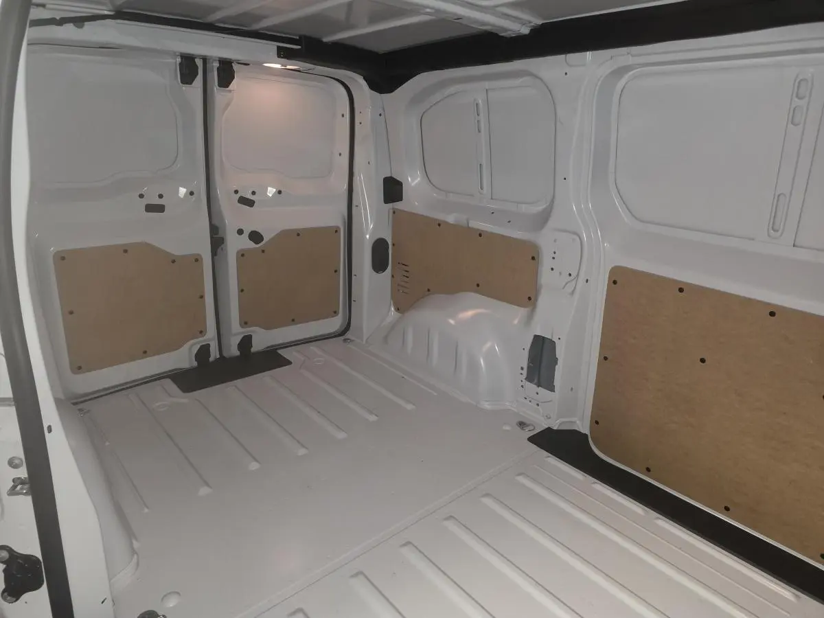 Vue intérieure arrière du fourgon blanc Opel Vivaro 2025, montrant l'espace de chargement avec panneaux de protection en bois.