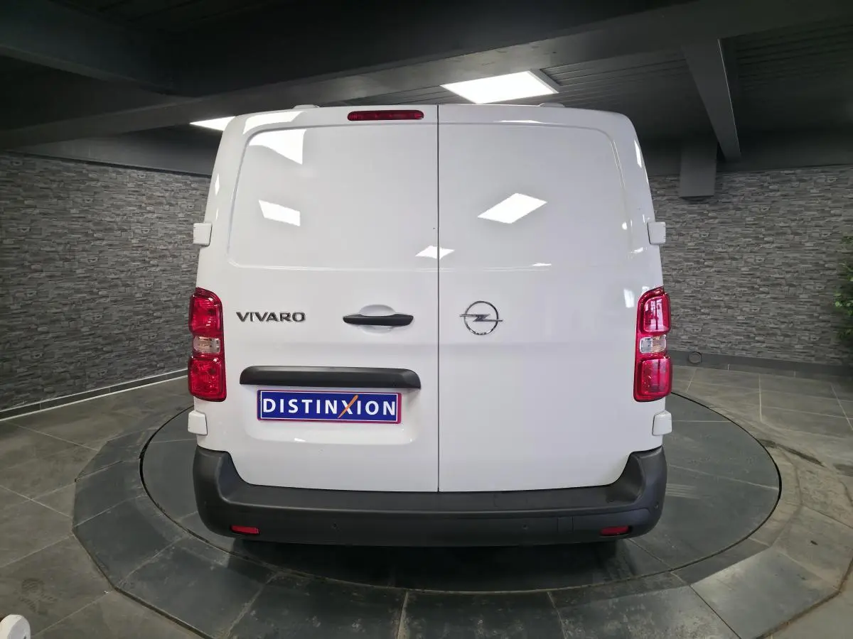 Vue arrière d’un Opel Vivaro blanc 2025 avec portes battantes et pare-chocs noir mat dans un showroom.