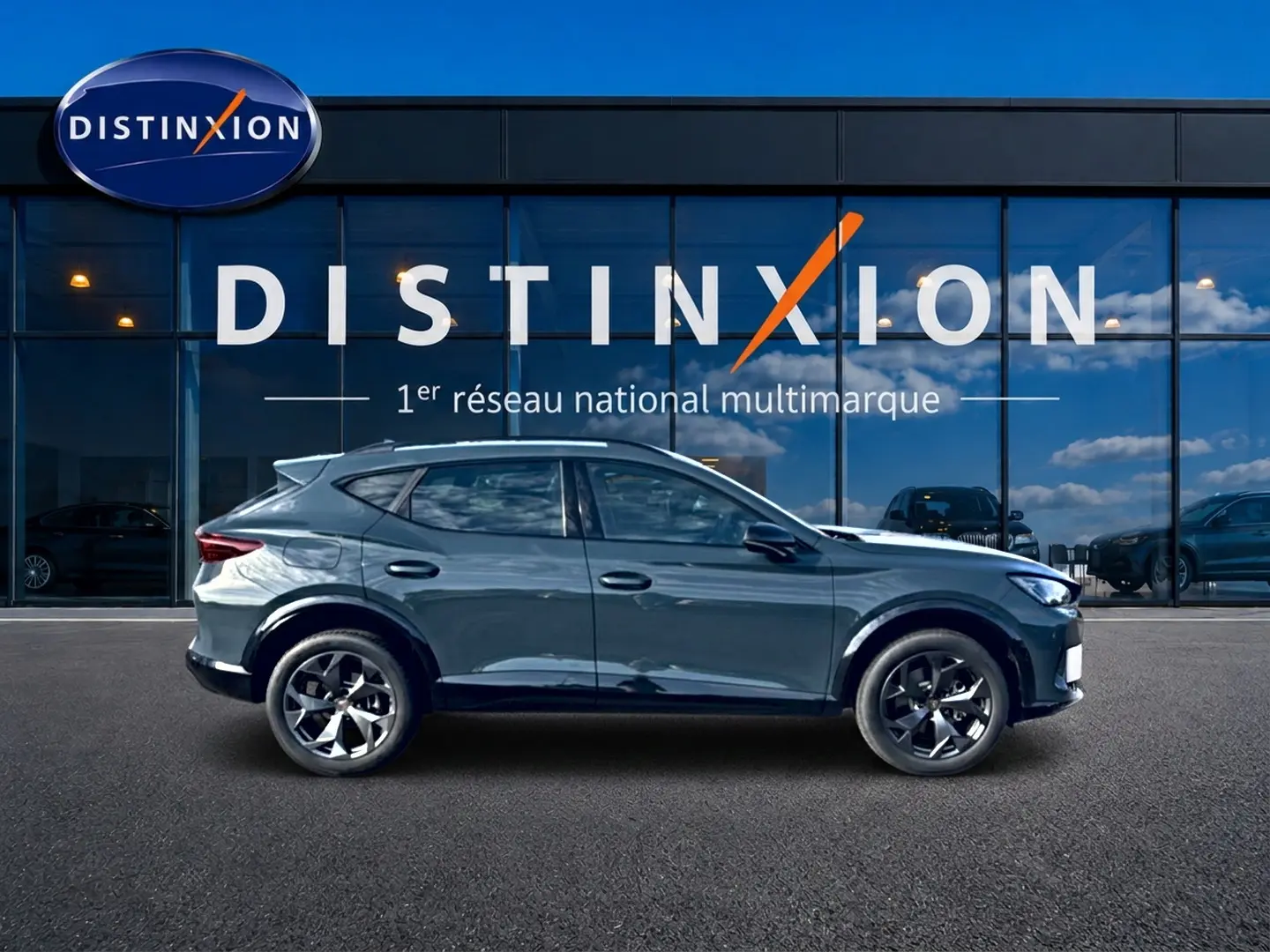 Vue de profil côté gauche d'un CUPRA Formentor bleu fjord 2026 devant une vitrine Distinxion.