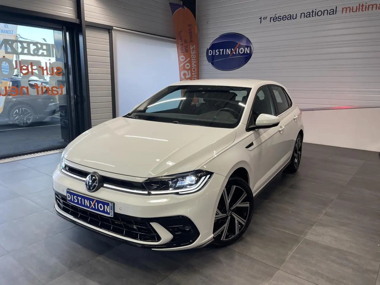Volkswagen Polo 2024 blanche vue 3/4 avant en intérieur avec jantes alliage R-Line et calandre spécifique.