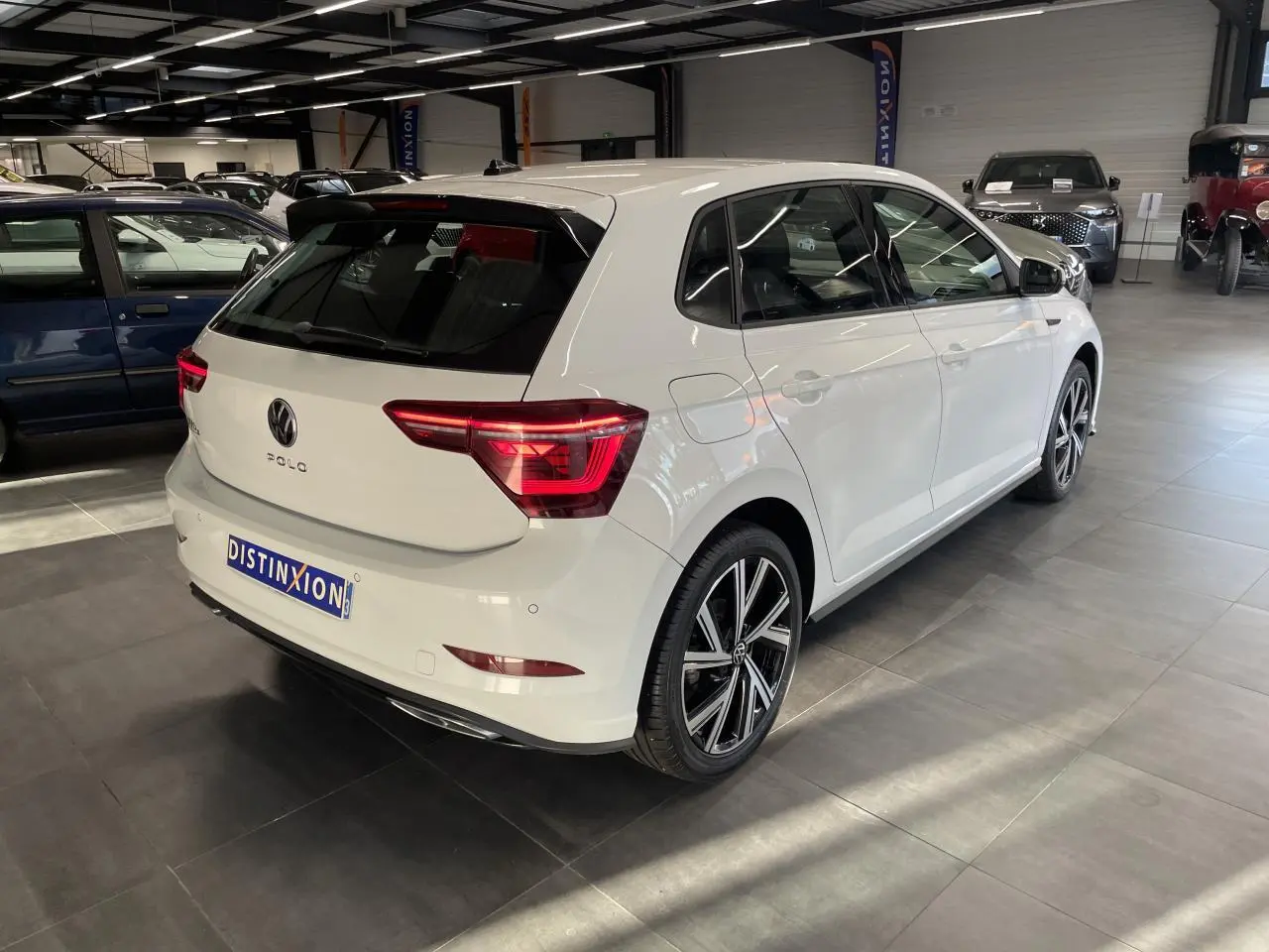 Vue 3/4 arrière droite d'une Volkswagen Polo blanche 2024 finition R-Line avec jantes alliage et feux LED distinctifs.