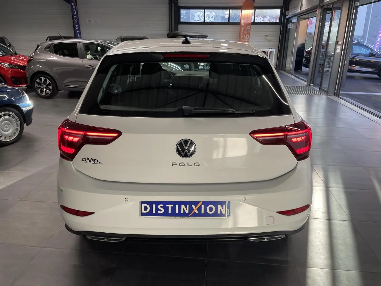 Vue arrière d'une Volkswagen Polo blanche 2024 R-Line avec feux LED et double sortie d'échappement en concession.