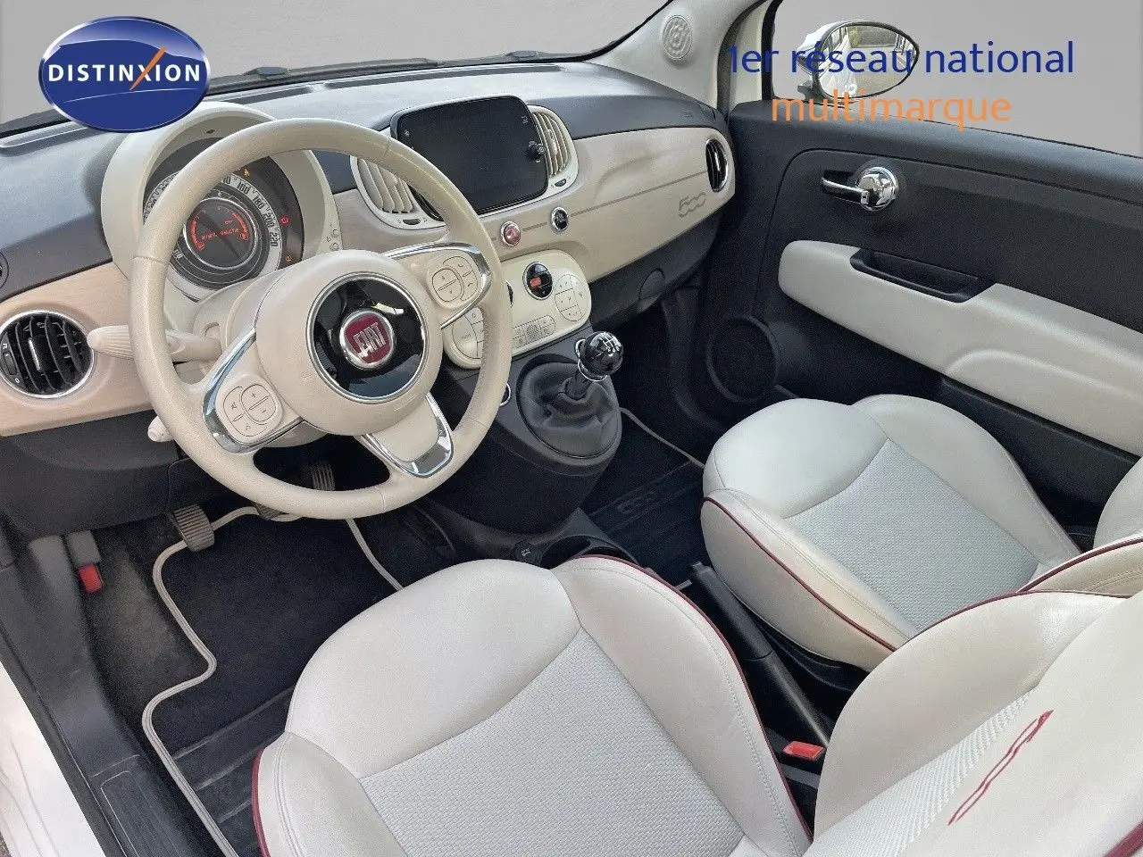 Intérieur avant droit de la FIAT 500 blanche 1.0 Hybrid 70ch DolceVita avec volant beige et sièges cuir clair.