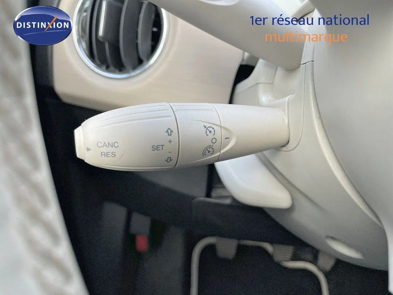 Gros plan sur la commande de régulateur de vitesse blanc dans l'habitacle clair d'une Fiat 500 blanche 2022.