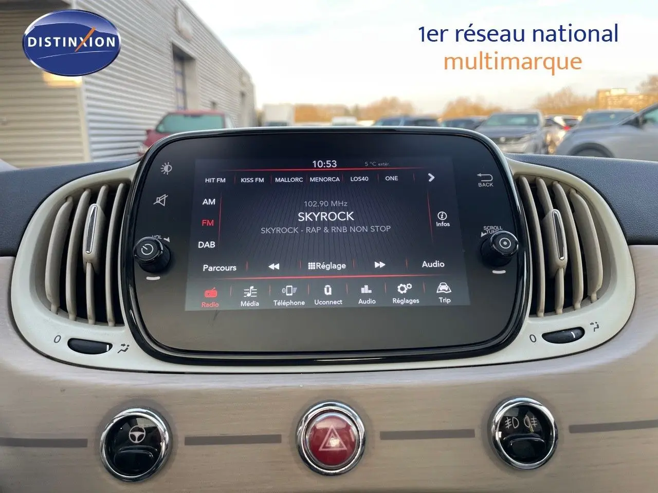 Tableau de bord de Fiat 500 blanc 2022 avec écran tactile central affichant la radio Skyrock, entouré de grilles d'aération ovales.