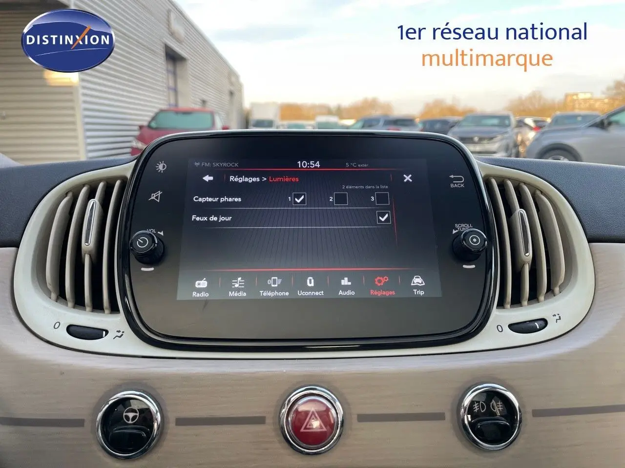 Tableau de bord beige clair de la Fiat 500 blanche 1.0 Hybrid 70CH DolceVita avec écran tactile central affichant les réglages lumières.