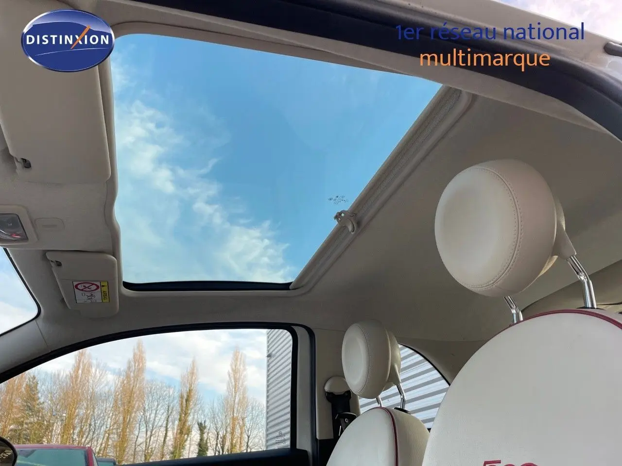 Intérieur clair de la Fiat 500 blanche 2022, vue sur toit ouvrant panoramique et sièges avant en cuir blanc.