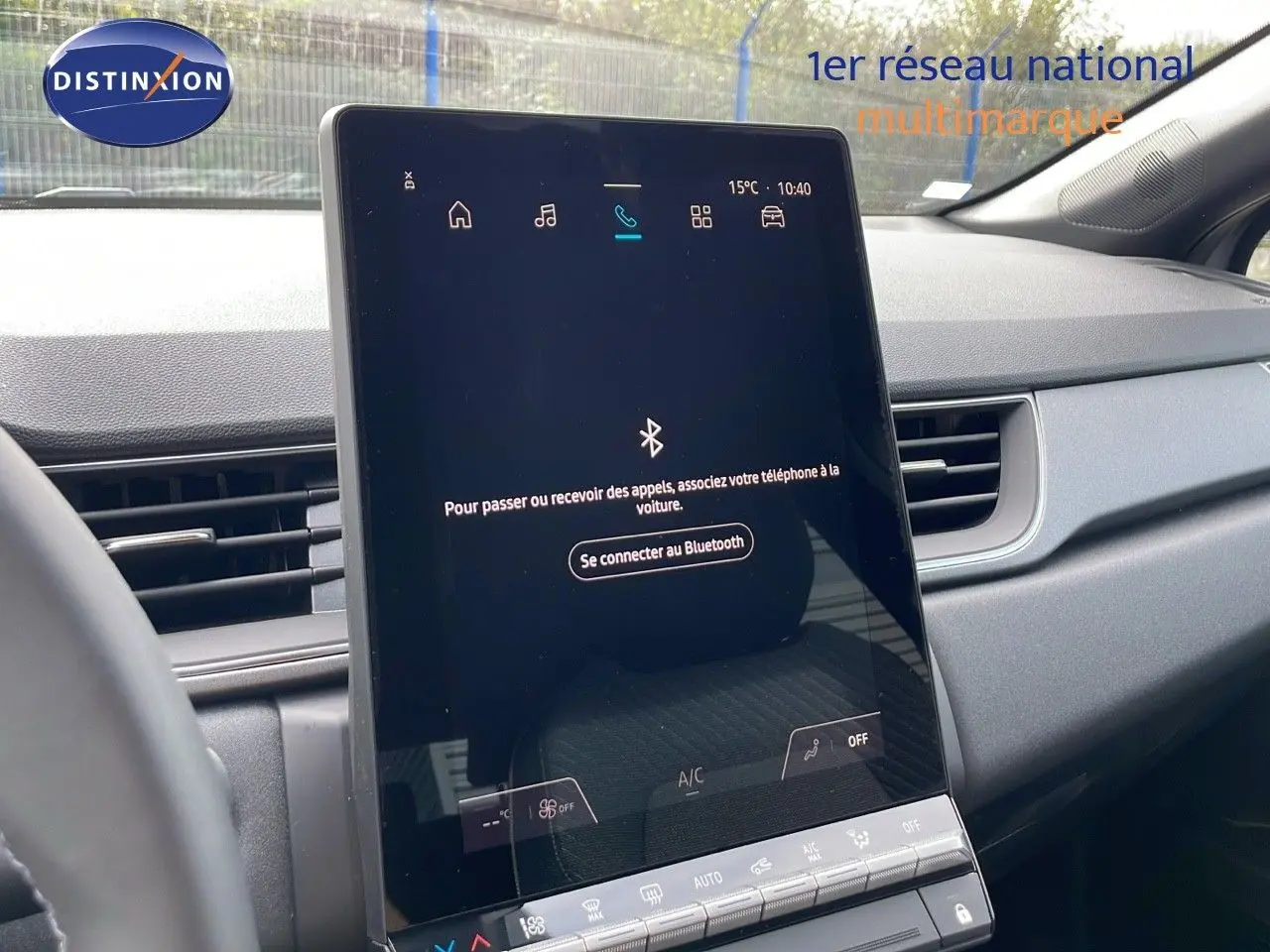 Écran tactile central allumé dans l'habitacle gris du Renault Captur E-Tech Hybrid 2025, vue de face côté conducteur.
