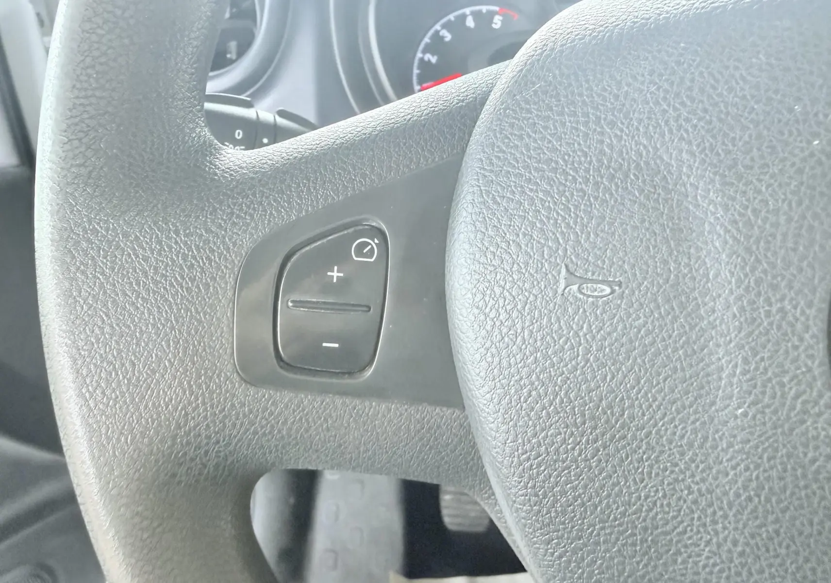 Gros plan sur le volant noir de l'Opel Vivaro 2018 avec commandes de régulateur de vitesse visibles à gauche.