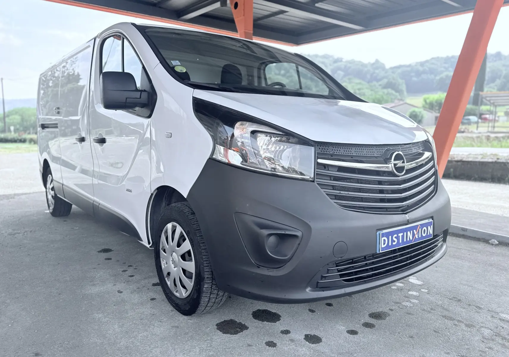 Vue 3/4 avant gauche d’un Opel Vivaro blanc avec pare-chocs avant noir mat sous abri.