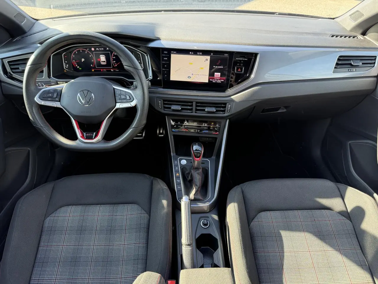 Vue intérieure frontale du tableau de bord et volant cuir GTI de la Volkswagen Polo 2.0 TSI 2024, sièges tissu à carreaux.