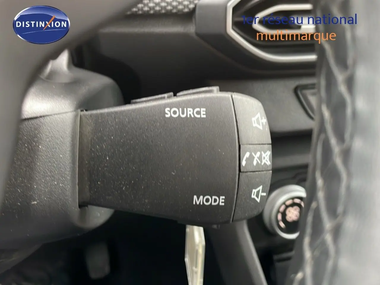 Gros plan sur la commande audio au volant d’un Dacia Jogger kaki lichen, intérieur noir visible en arrière-plan.