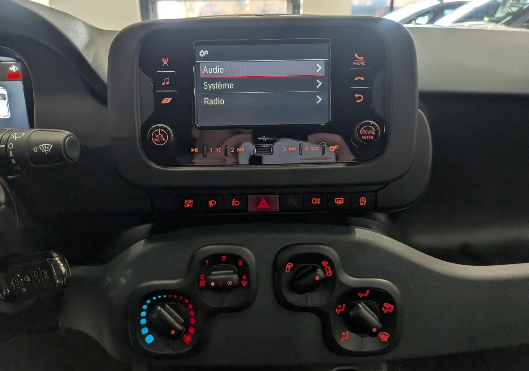 Vue rapprochée du tableau de bord de la Fiat Panda 2025 blanc Gelato, avec écran tactile et commandes climatiques manuelles.