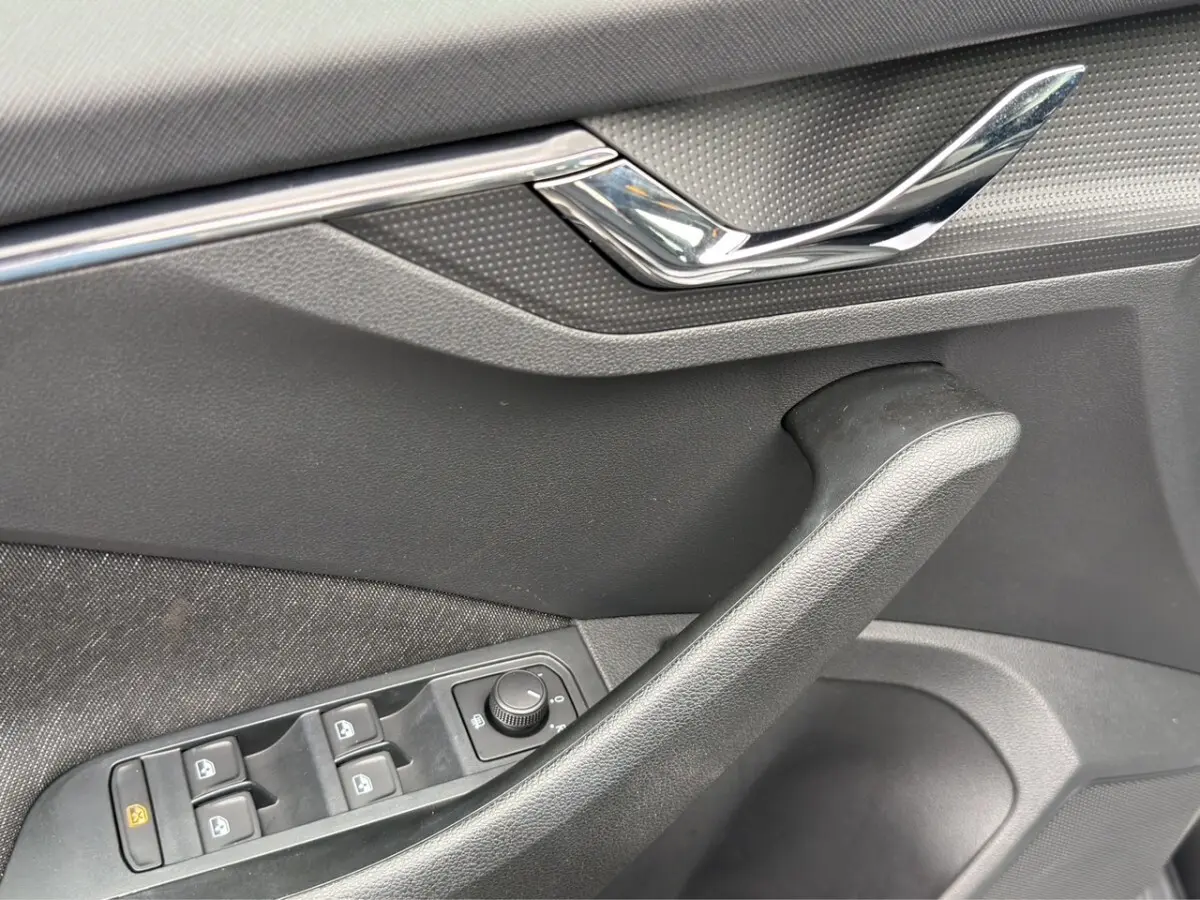 Détail de la porte côté conducteur du Skoda Kamiq gris foncé, avec commandes électriques des vitres et poignée noire.
