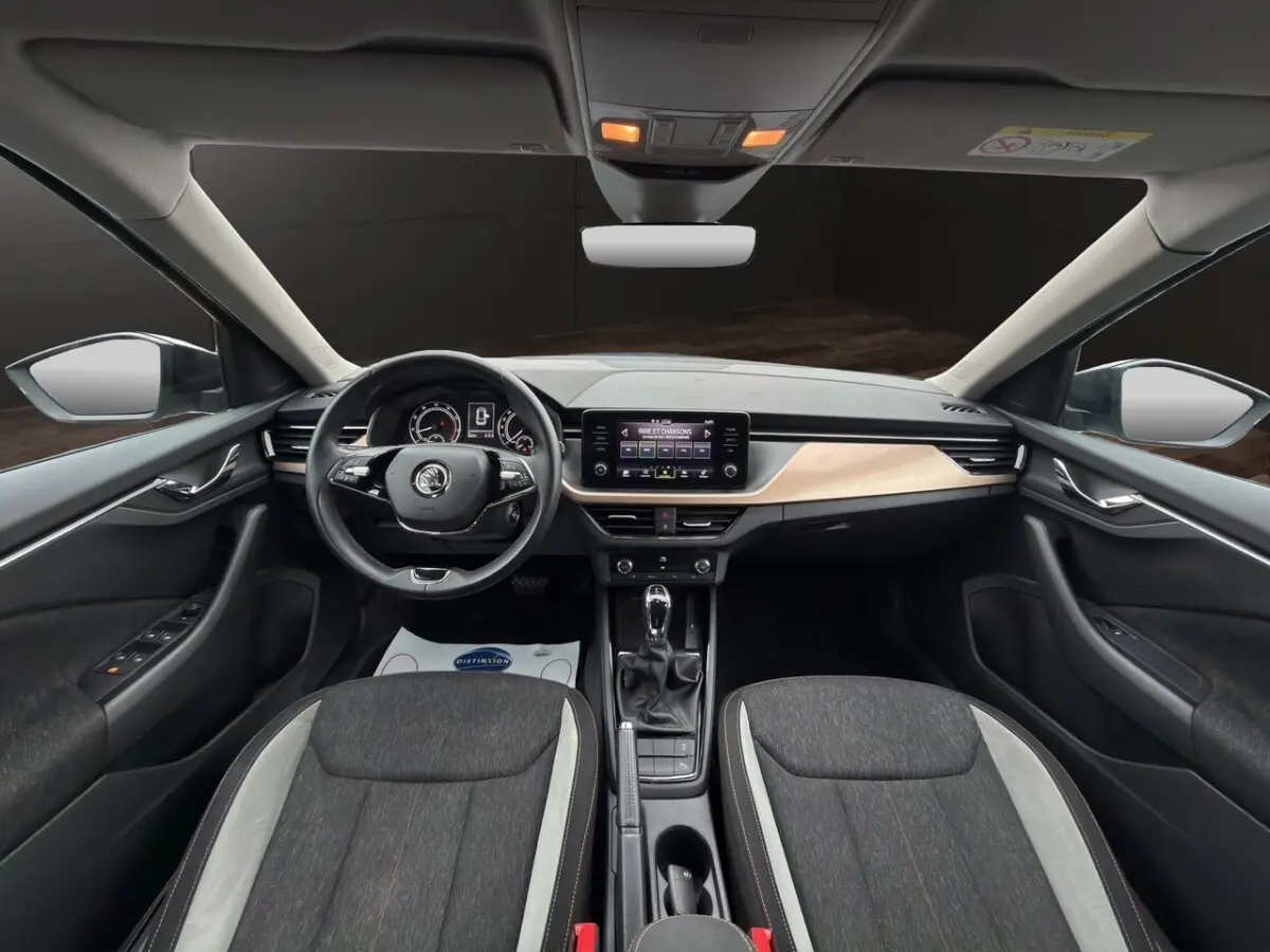 Vue intérieure avant du Skoda Kamiq 2023, tableau de bord clair avec écran tactile et sièges bi-ton gris foncé et clair.