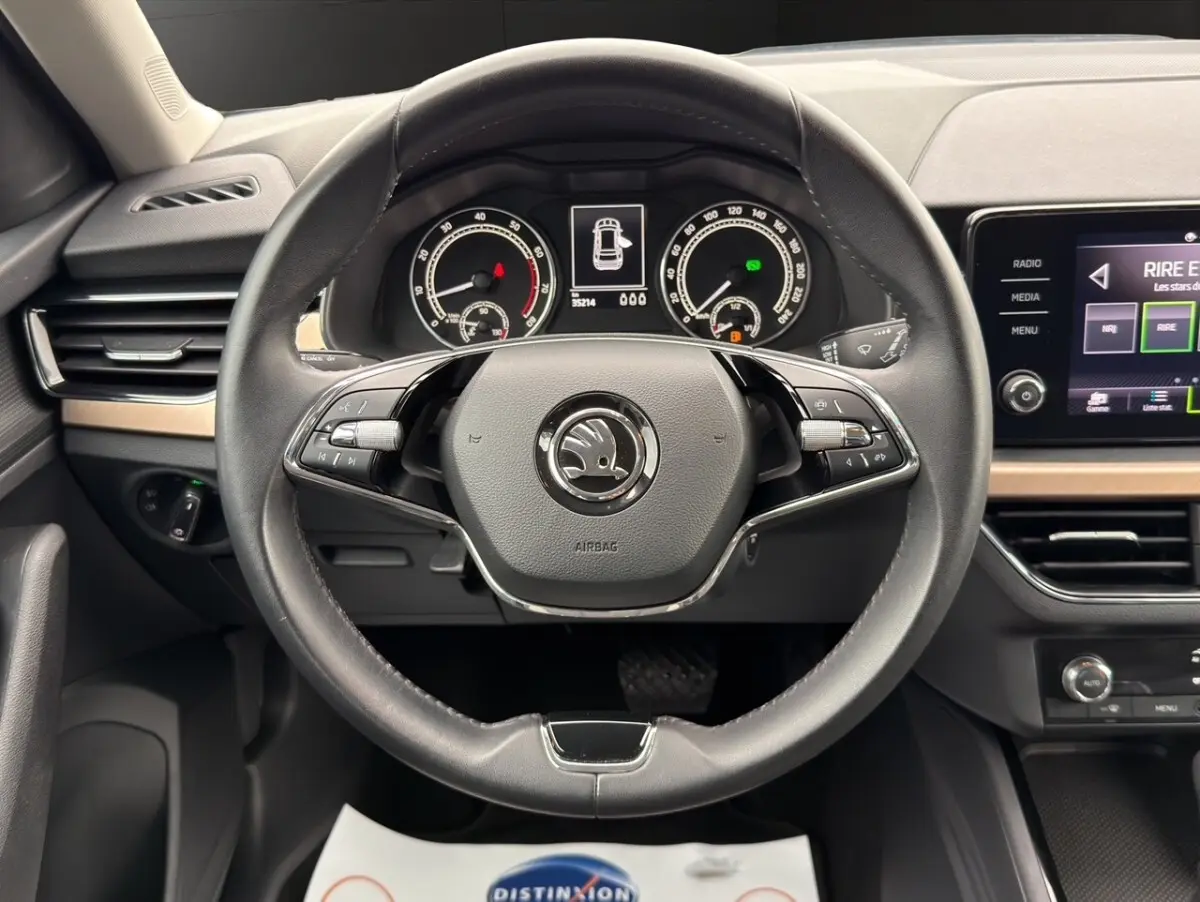 Vue centrée sur le volant cuir noir et le combiné d'instruments numérique du Skoda Kamiq 2023, tableau de bord bois clair.