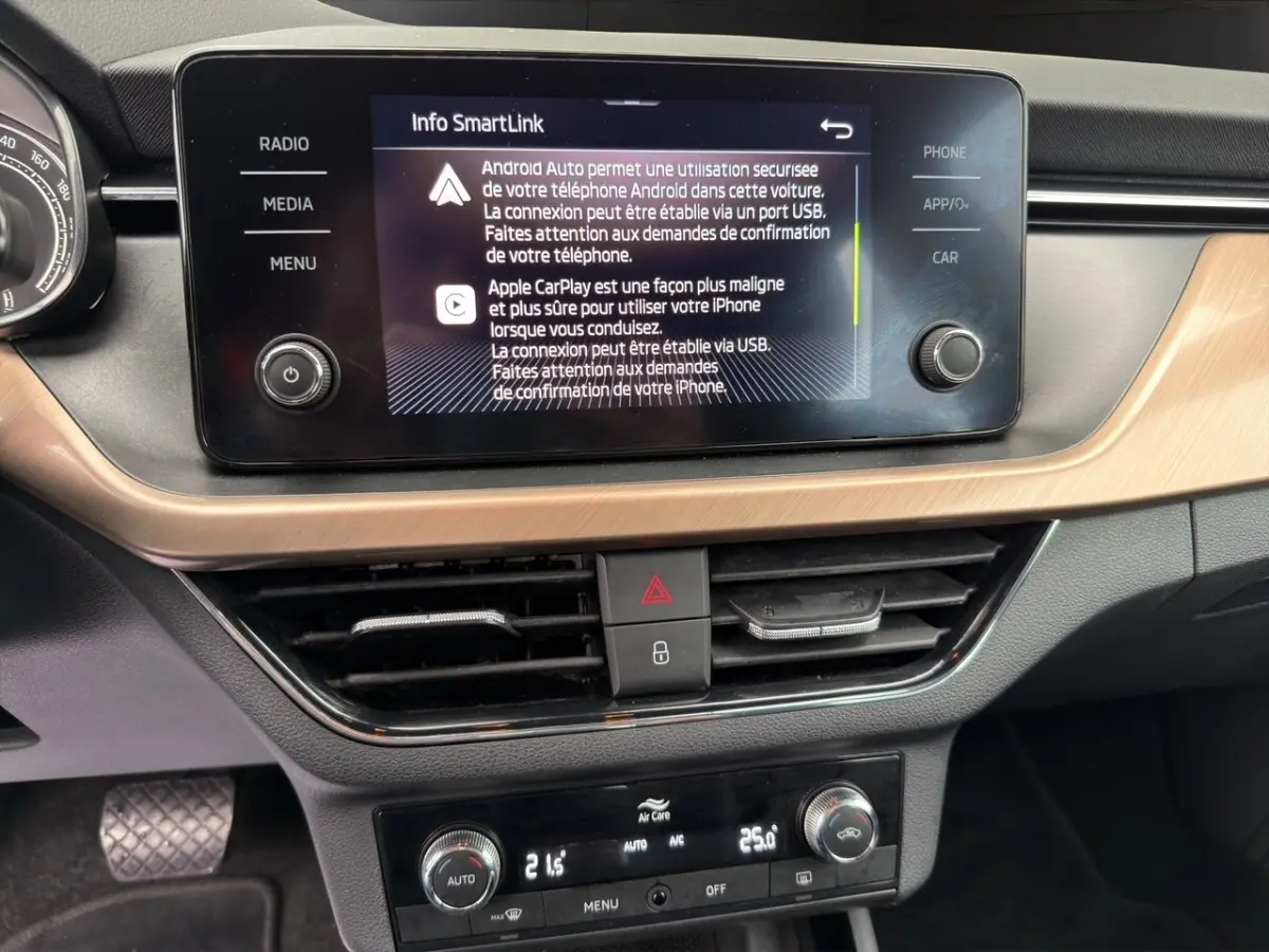 Vue rapprochée du tableau de bord du Skoda Kamiq 2023, écran tactile central affichant SmartLink, finition bois clair.