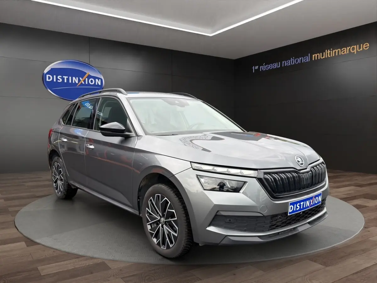 Vue 3/4 avant droite d'un Skoda Kamiq gris foncé avec jantes bi-ton et calandre noire en showroom.