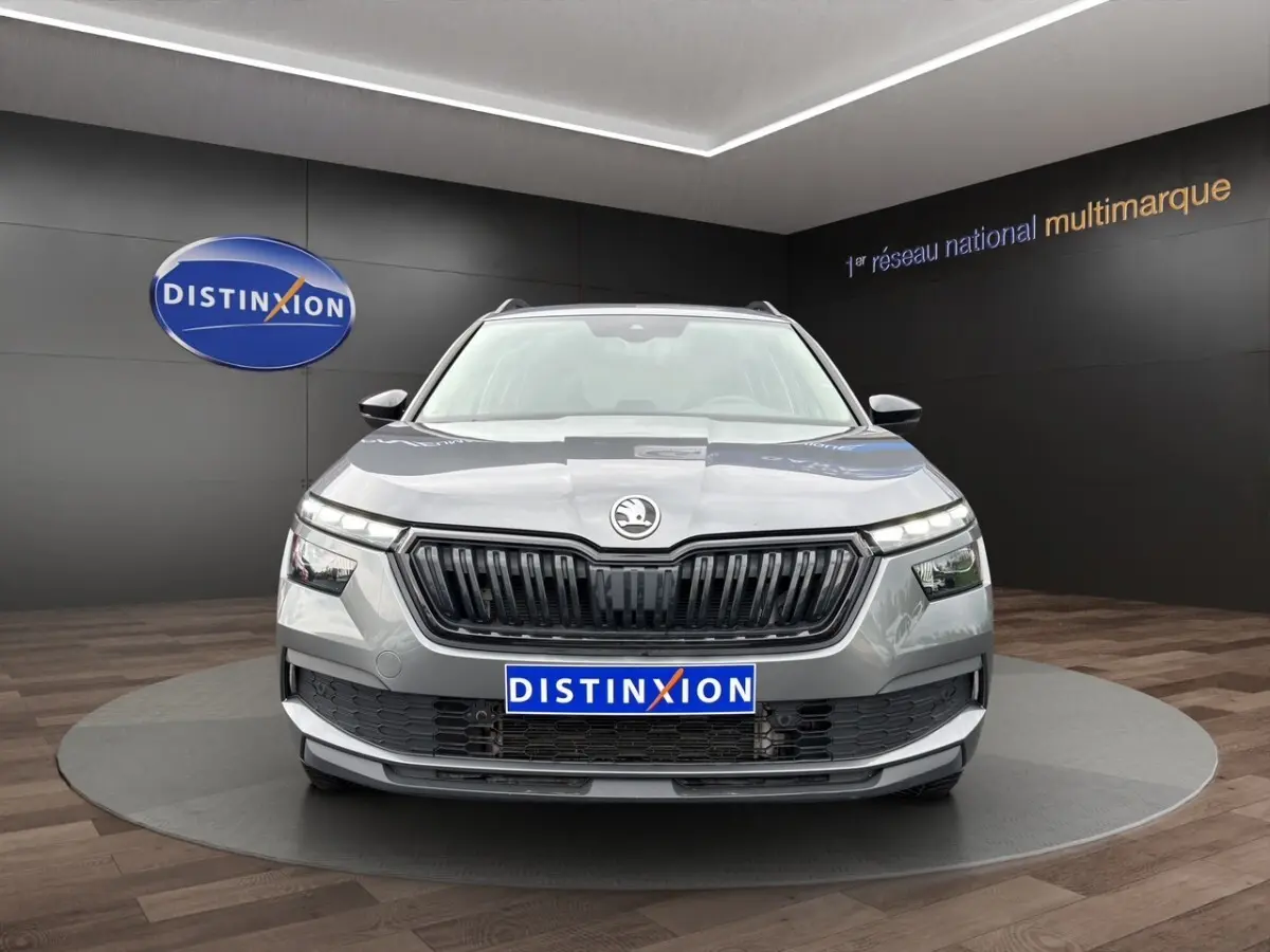 Vue avant d'un Skoda Kamiq gris foncé avec calandre noire et logo centré, présenté en showroom Distinxion.