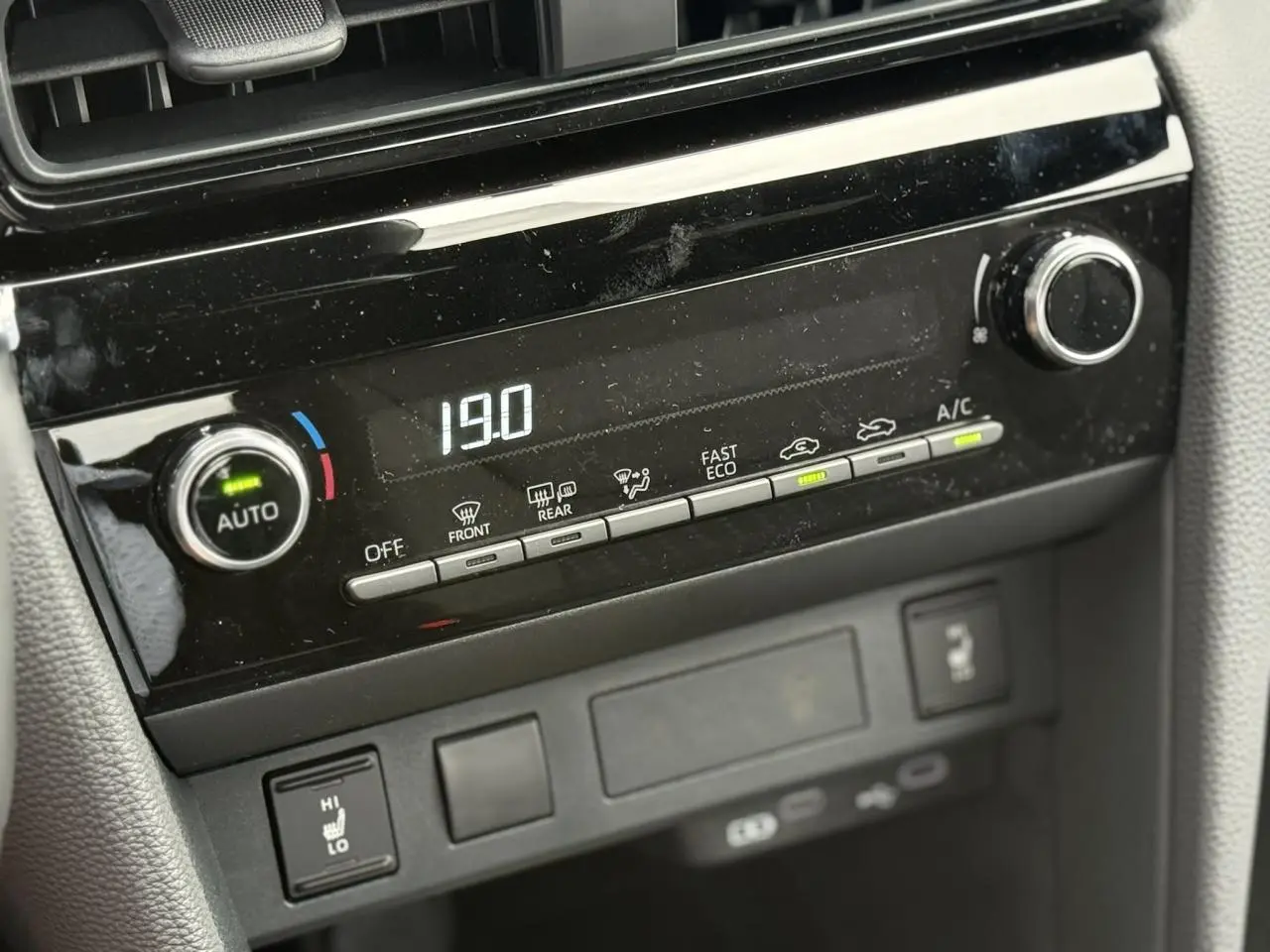 Gros plan sur la console centrale noire du Toyota Yaris Cross blanc avec affichage digital de la climatisation à 19°C.