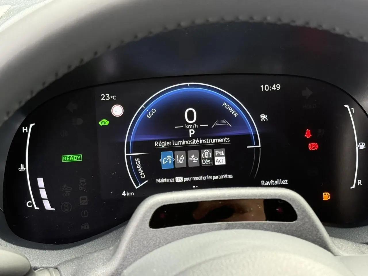 Vue rapprochée du tableau de bord numérique de la Toyota Yaris Cross blanc lunaire, affichant les instruments et alertes.