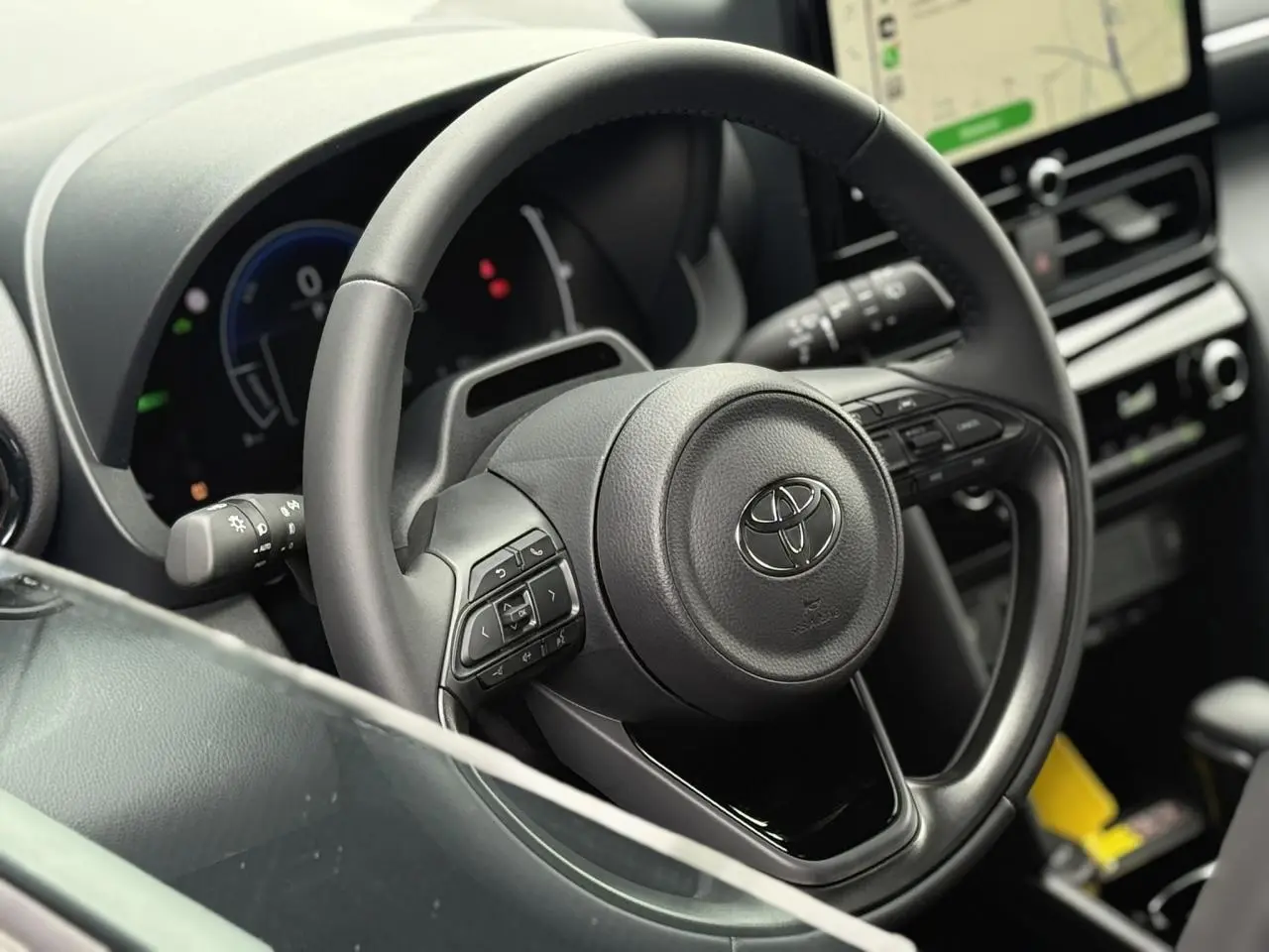 Gros plan sur le volant cuir noir de la Toyota Yaris Cross 2026 avec tableau de bord et écran tactile en arrière-plan.