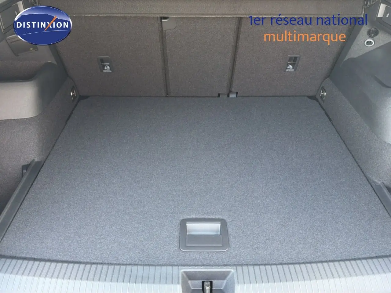 Vue du coffre spacieux et plat du Volkswagen Tiguan gris dauphin métal, montrant le revêtement intérieur uniforme et les fixations arrière.