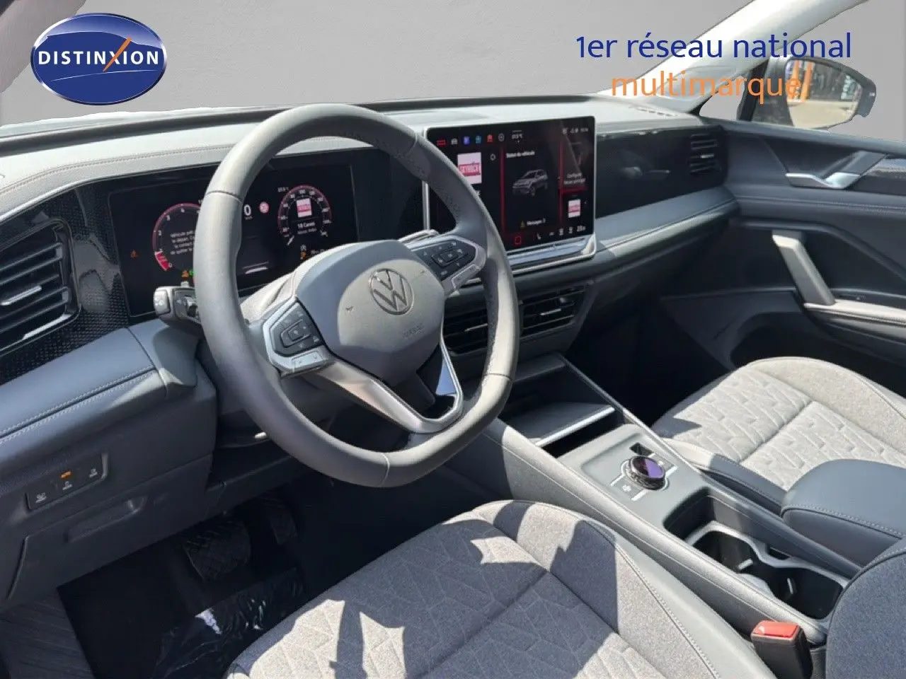 Vue intérieure du Volkswagen Tiguan 2026 montrant le tableau de bord et le volant avec écran tactile et sellerie grise.