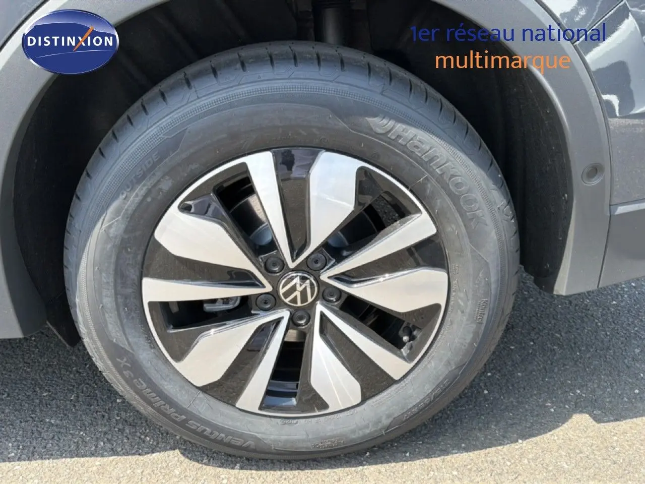 Gros plan sur la roue avant droite du Volkswagen Tiguan gris dauphin métal avec jante alliage bicolore moderne.