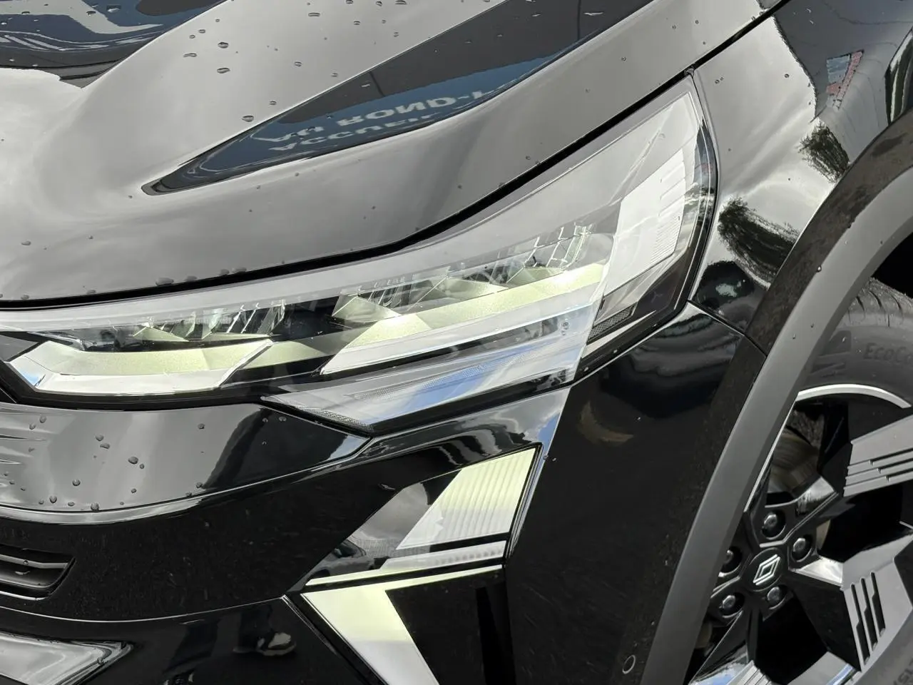 Gros plan sur le phare avant droit et la jante noire du Renault SYMBIOZ noir étoile 2025.