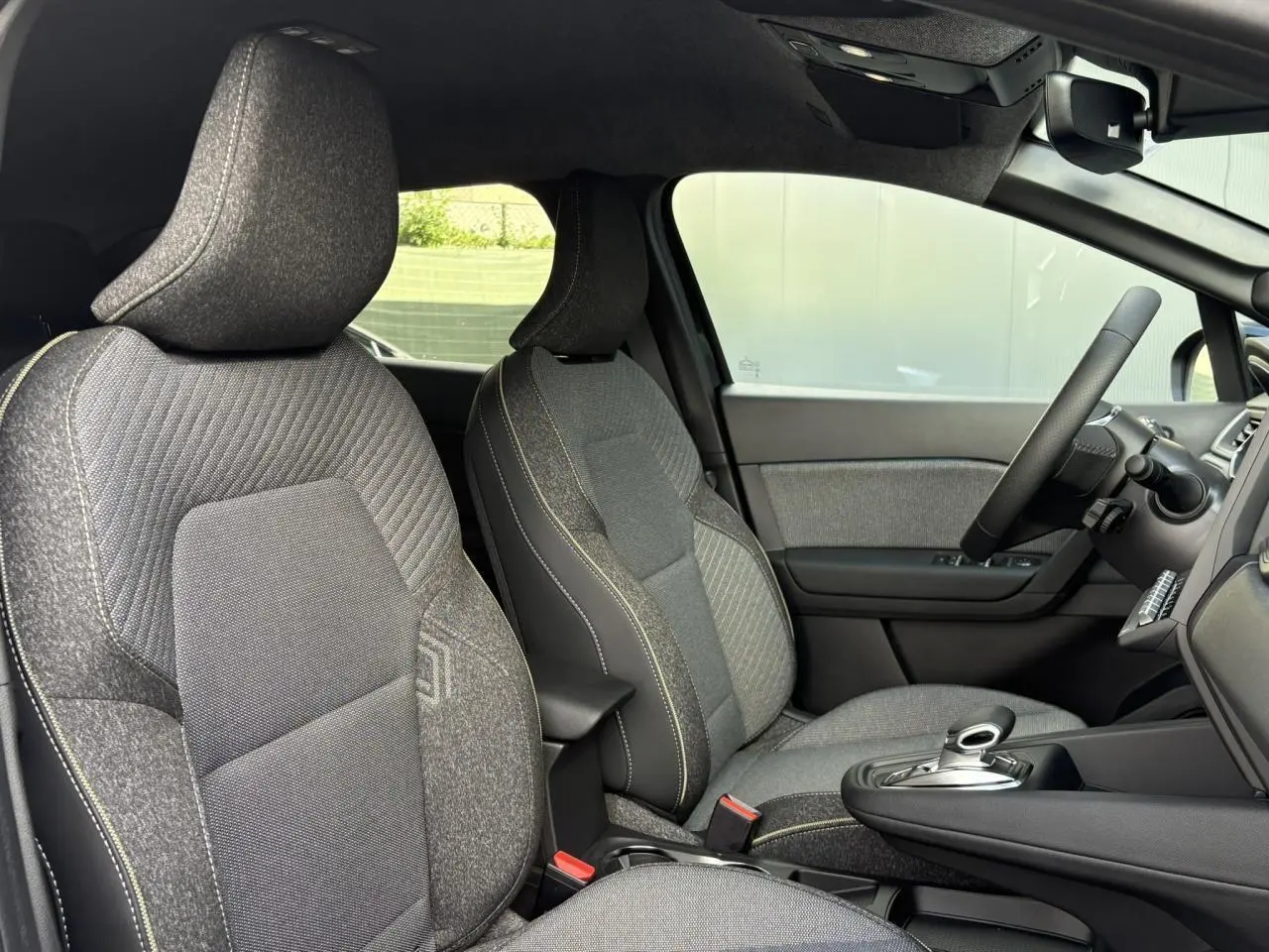 Vue intérieure côté droit du Renault SYMBIOZ 2025, sièges tissu gris avec console centrale et volant multifonction.