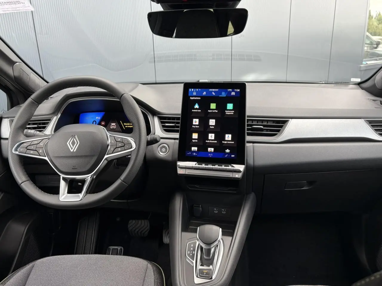 Vue intérieure frontale du tableau de bord et volant Renault Symbioz 2025 avec écran tactile vertical et commandes au volant.