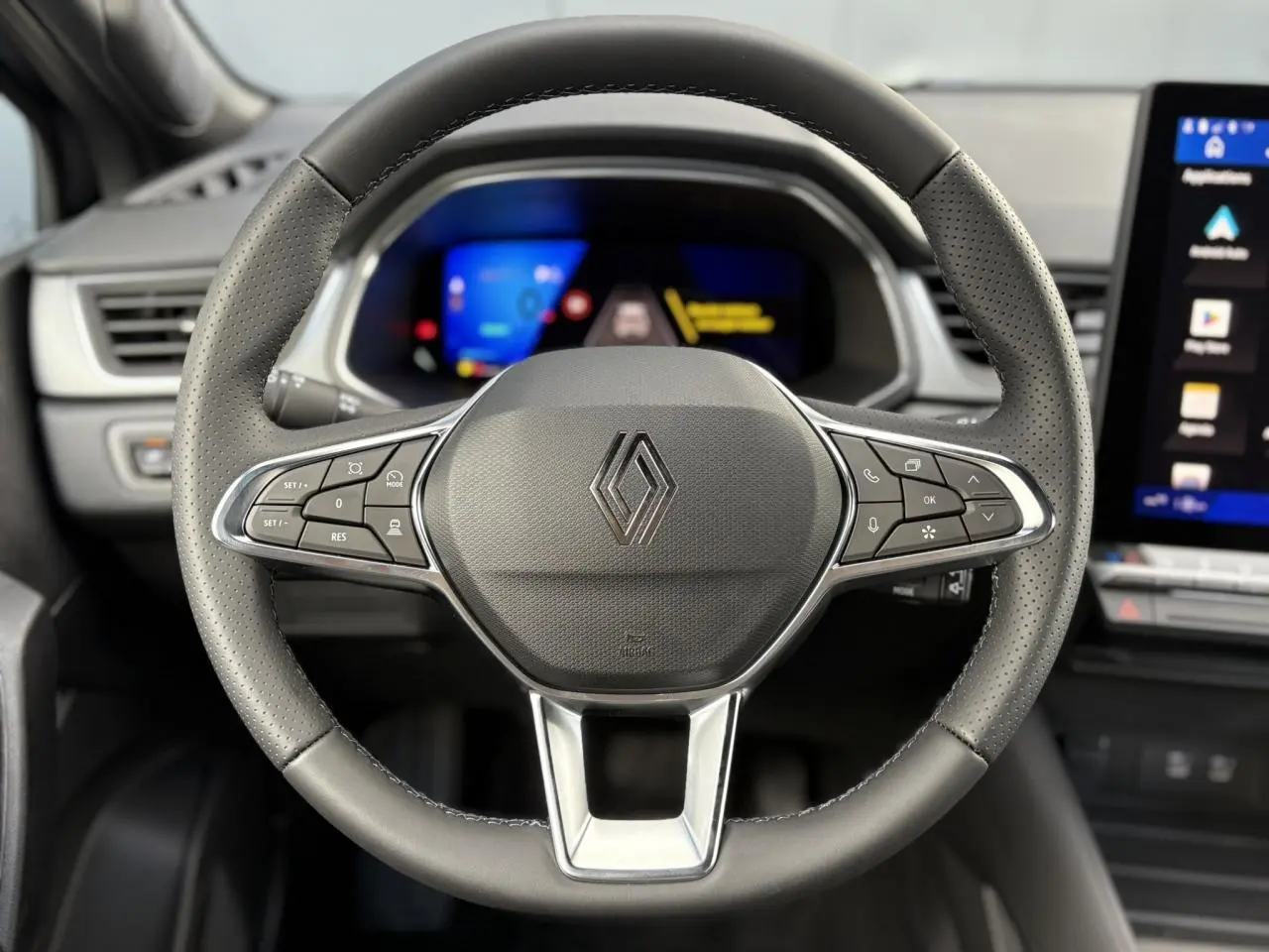 Volant multifonction en cuir noir avec logo Renault, tableau de bord numérique et écran tactile latéral dans un Renault SYMBIOZ 2025.