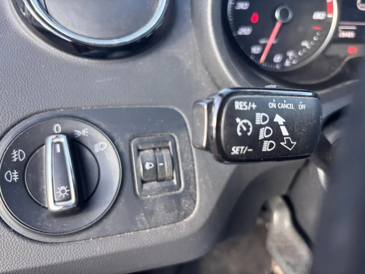 Gros plan sur les commandes d'éclairage et régulateur de vitesse du tableau de bord d'une SEAT Ibiza 2016 rouge clair.