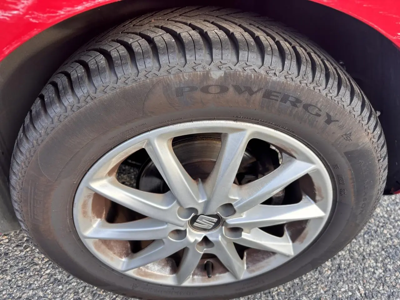 Gros plan sur la roue avant gauche d'une SEAT Ibiza rouge clair de 2016, mettant en valeur la jante alliage et le pneu Powergy.