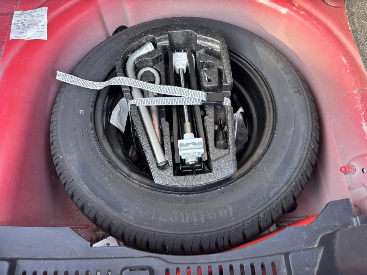 Roue de secours et outils de bord dans le coffre rouge clair d'une SEAT Ibiza 1.2 TSI Style 2016.