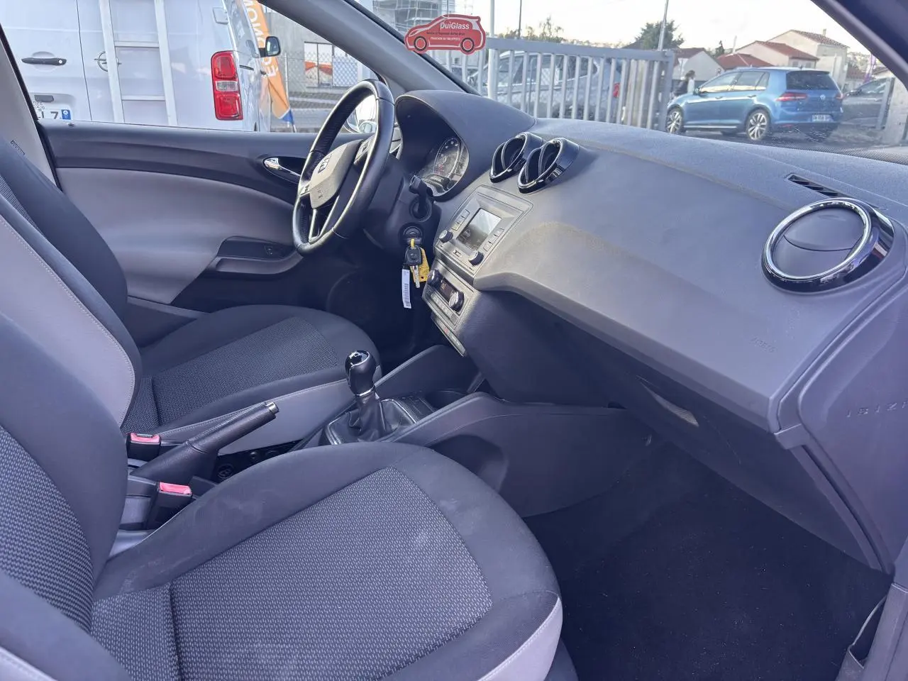 Intérieur de la SEAT Ibiza 1.2 TSI Style 2016, vue côté conducteur montrant tableau de bord et sièges noirs.