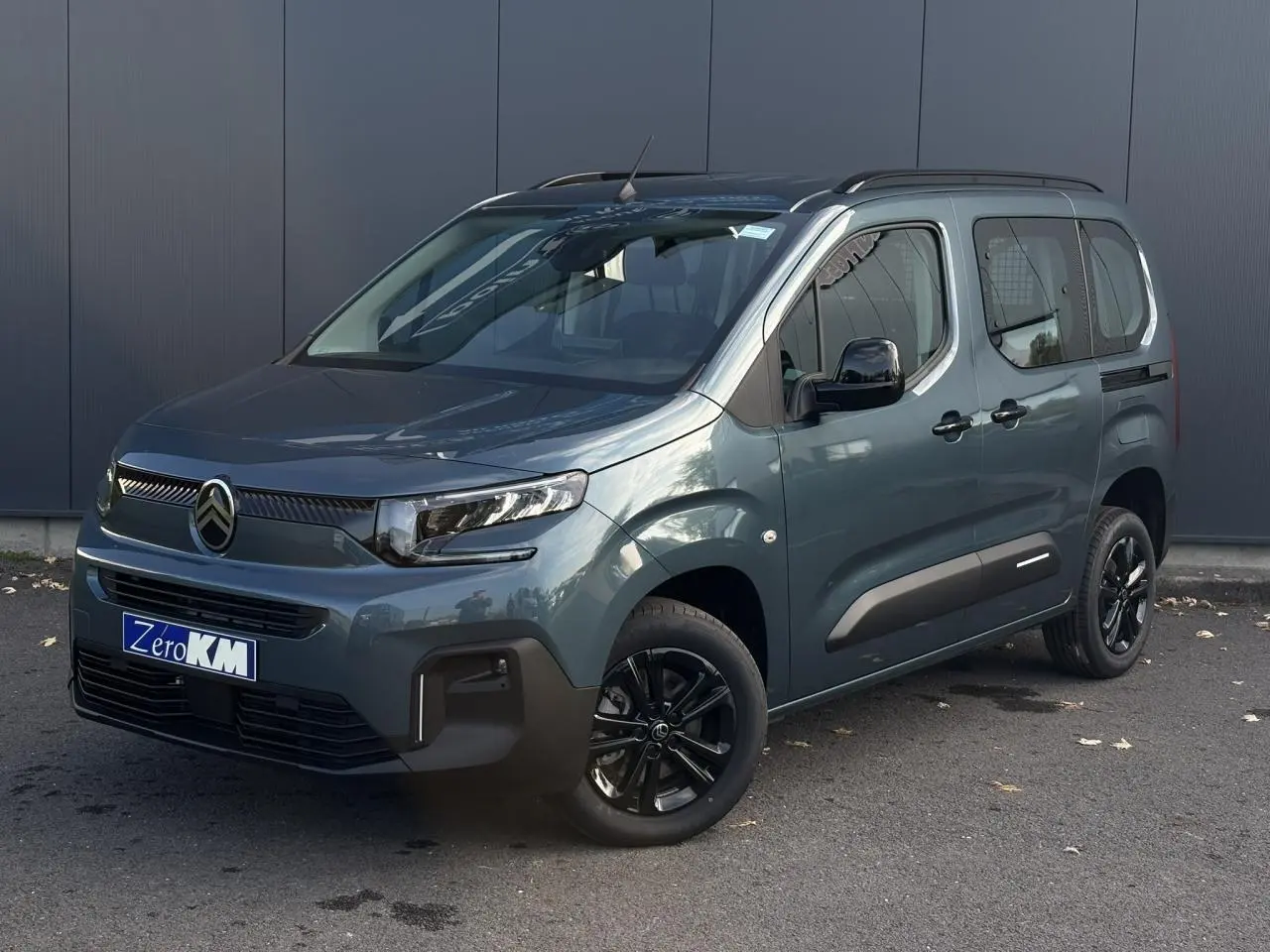 Vue 3/4 avant droit d'un Citroën Berlingo Multispace bleu métallisé avec jantes noires et barres de toit noires.