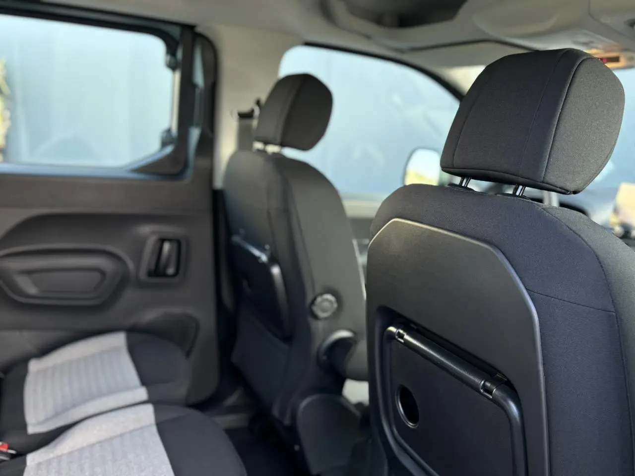 Vue intérieure des sièges arrière et des dossiers avant du Citroën Berlingo Multispace bleu, avec tablette aviation intégrée.
