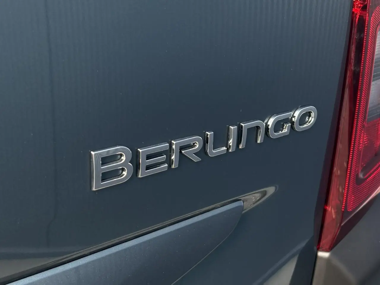 Gros plan sur l'arrière bleu métallisé du Citroën Berlingo 2025 avec logo et feu arrière rouge visible.