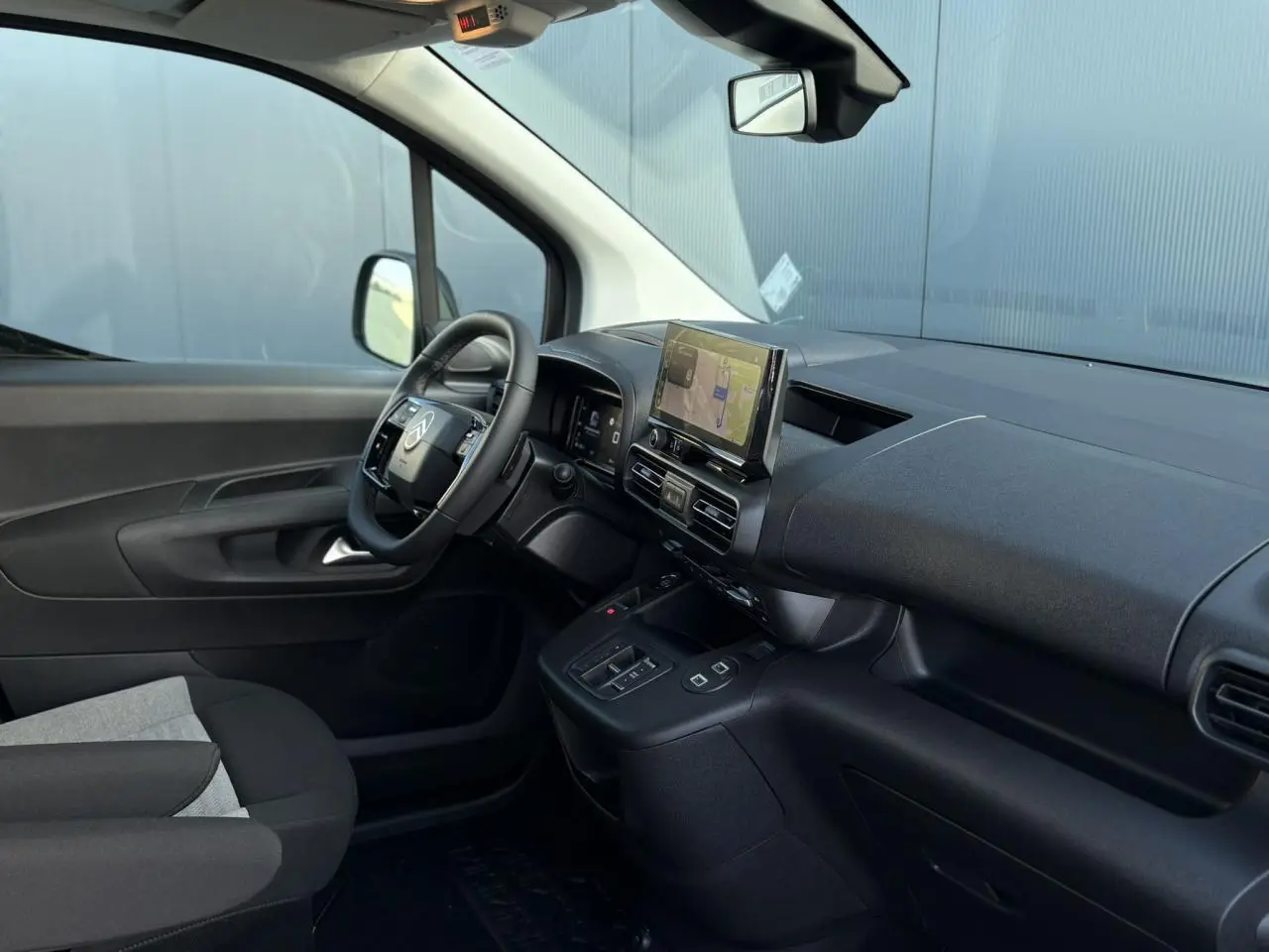 Intérieur du Citroën Berlingo Multispace 2025 vu côté conducteur, tableau de bord noir avec écran tactile et volant multifonctions.