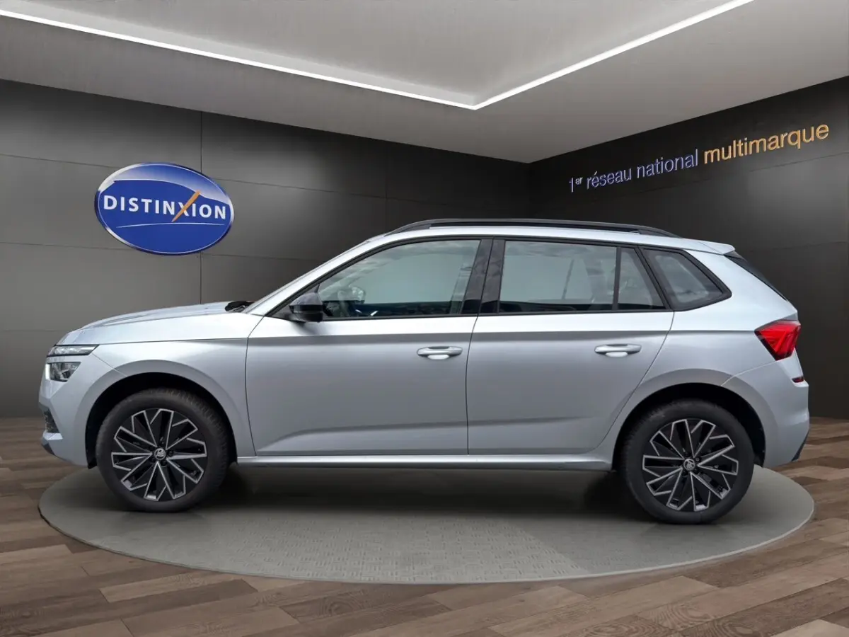 Vue 3/4 avant d'un Skoda Kamiq gris clair avec jantes bi-ton et rétroviseurs rabattables électriquement.